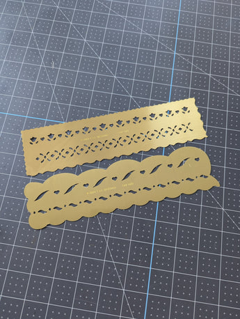 Two decorative metal cutting dies on a grid background